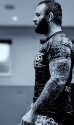 Chris looking to the left of the screen, with a Scoundrels Grappling rash guard on display